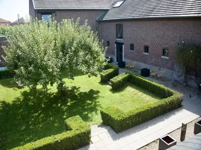 a garden with hedges and a tree and a building at Monastery Retreat in Blossoming Limburg in Sint-Truiden
