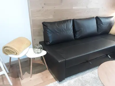 a black leather couch in a living room with a table at Hébergement Les Heros in Liège