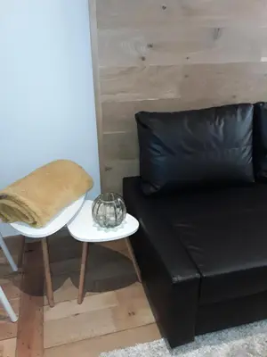 a black leather couch with a table and a stool at Hébergement Les Heros in Liège
