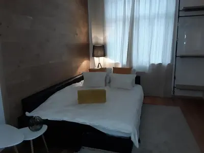 a bedroom with a bed with white sheets and pillows at Hébergement Les Heros in Liège