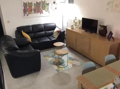 a living room with a black leather couch and a tv at Acacia 1 Hengelhoef in Houthalen-Helchteren