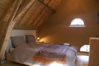 a bedroom with a bed and two windows at B&B De Metstermolen in Sint-Truiden