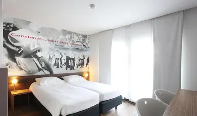 a bedroom with two beds and a poster on the wall at Hotel De Pits in Heusden - Zolder