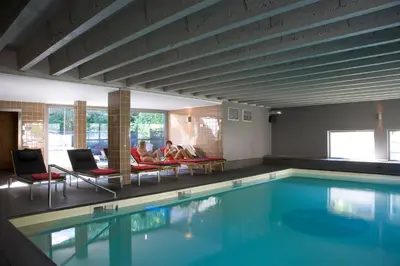 a swimming pool with two people sitting in chairs next to it at Hotel De Pits in Heusden - Zolder