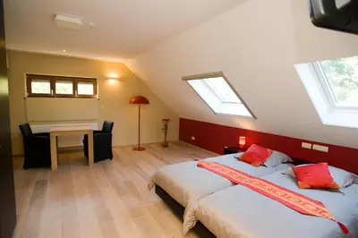 a attic bedroom with two beds and a desk and windows at De kiezel in Hasselt
