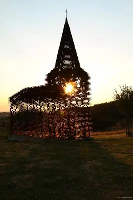 a sun setting behind a wooden structure in a field at B&B Het Loonderhof in Borgloon