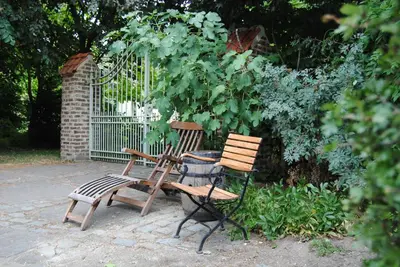 two wooden chairs and a trash can next to a fence at B&B Het Loonderhof in Borgloon