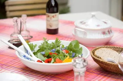 a salad in a bowl on a table with a bottle of wine at B&B Het Loonderhof in Borgloon