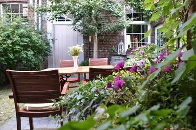 a table and chairs in a garden with flowers at B&B Het Loonderhof in Borgloon