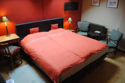 a bedroom with a bed with red walls and chairs at B&B Het Loonderhof in Borgloon