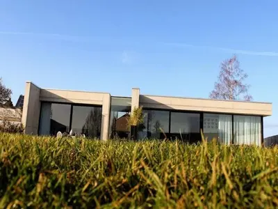 a building with glass windows on a field of grass at Cozy Villa in Dalhem Ardennes with Private Garden in Dalhem