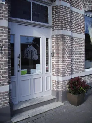 a white door on a brick building with a window at Hotel Hooghuys in Hamont-Achel