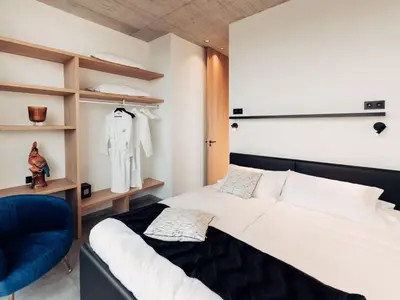 a bedroom with a white bed and a blue chair at Modern Dalhem Villa with Views in Dalhem
