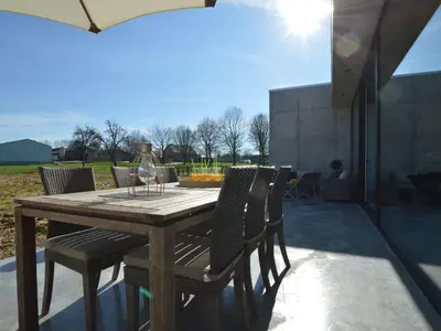 a wooden table with chairs and a wine glass at Modern Dalhem Villa with Views in Dalhem