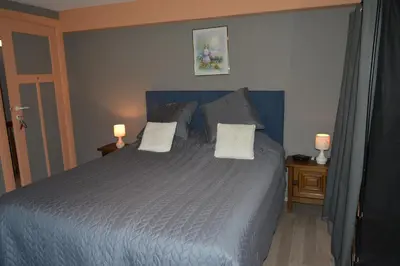 a bedroom with a blue bed with two lamps on tables at Julienne5 in Blégny