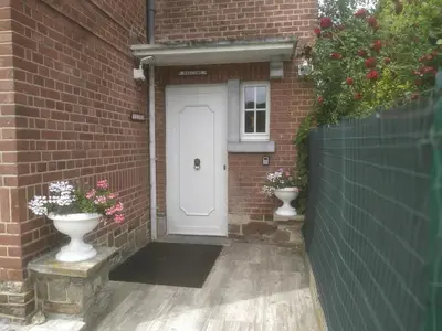 a white door in a brick building with two vases at Julienne5 in Blégny