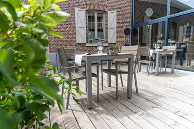 a wooden deck with tables and chairs on a building at Hotel De Maretak in Dilsen-Stokkem