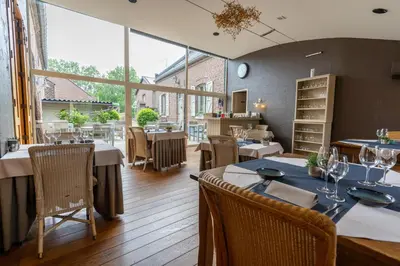 a restaurant with tables and chairs and large windows at Hotel De Maretak in Dilsen-Stokkem