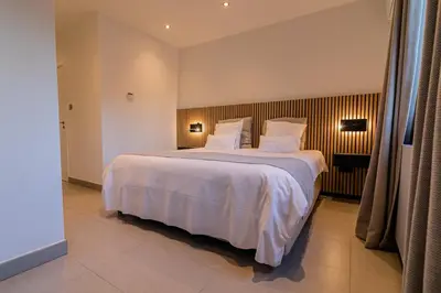 a bedroom with a large bed with white sheets and pillows at B&B Villa Curtricias in Kortessem