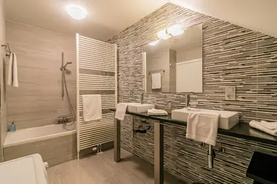 a bathroom with two sinks and a mirror and a tub at B&B Villa Curtricias in Kortessem