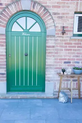 a green door on a brick wall with a table at 'Op de Borgt' met Finse Grill Kota in Wellen