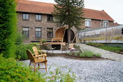a garden with chairs and a table in front of a building at De Mandenvlechter in Dilsen-Stokkem