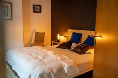 a bedroom with a large white bed with blue pillows at De Mandenvlechter in Dilsen-Stokkem