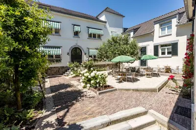 a house with a patio with tables and umbrellas at B&B Hostellerie Marie in Eben-Emael
