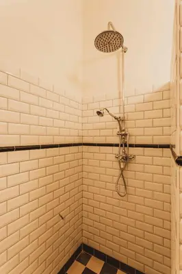 a shower in a white tiled bathroom with a shower head at B&B Hostellerie Marie in Eben-Emael