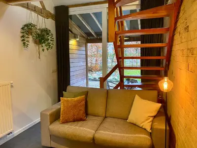 a living room with a couch and a staircase at Landgoed De Hoogmolen in Oudsbergen