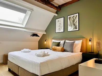 a bedroom with a large white bed with a window at Landgoed De Hoogmolen in Oudsbergen