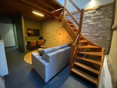 a living room with a couch and a staircase at Landgoed De Hoogmolen in Oudsbergen