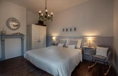 a bedroom with a bed and a chair and a chandelier at Stadshuisje 36 in Hasselt