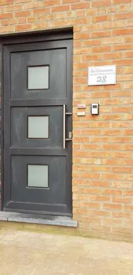 a black door on the side of a brick building at LA BINAMERIE in Remicourt