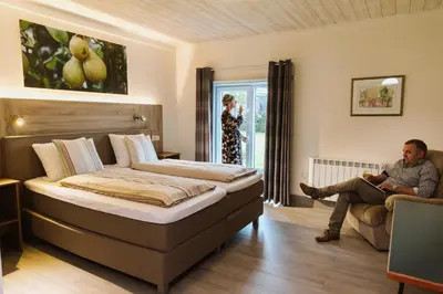 a man sitting on a chair in a bedroom with a bed at Gasthof De Statie in Wilderen