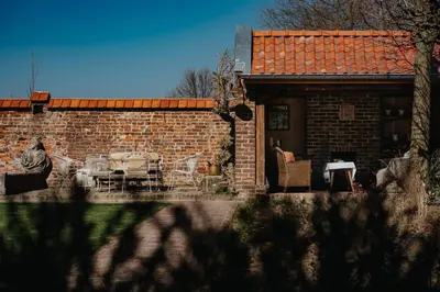 a brick house with a table and chairs in a yard at Amitié in Kinrooi