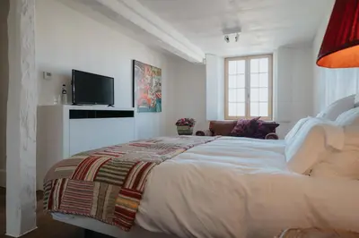 a white bedroom with a bed and a tv at Amitié in Kinrooi