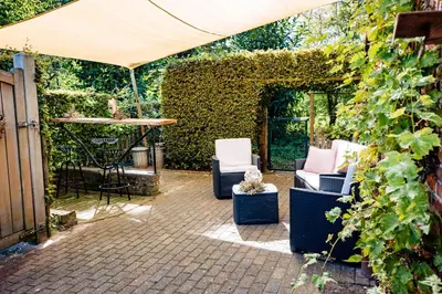 a patio with two chairs and a table and an umbrella at Bij de Zöster in Kinrooi