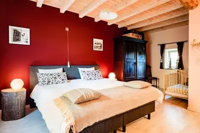 a bedroom with red walls and a large bed at Bij de Zöster in Kinrooi