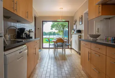 a kitchen with wooden cabinets and a table with chairs at Vakantiewoning ‘t Reigersnest in Zonhoven