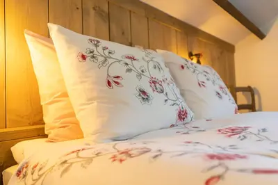 a bed with white sheets and red flowers on it at Bed & Breakfast 't Vèèrke in Dilsen-Stokkem
