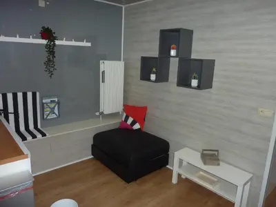 a living room with a black chair and a table at Vakantie woning De Loft in Dilsen-Stokkem