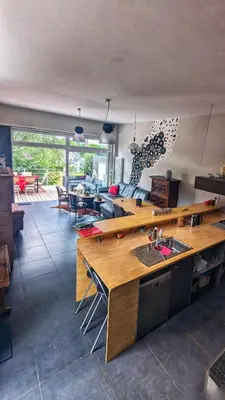 a living room with a kitchen with a counter and a table at Maison à la porte des Ardennes in Verviers
