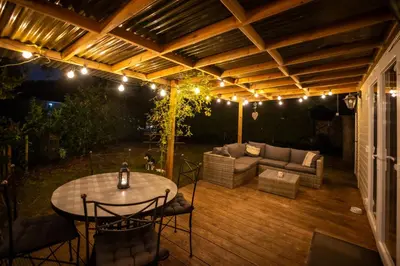 a patio with a table and a couch on a deck at Chalet de bosuil in Zutendaal