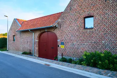 a red brick building with a red garage at Boerderaaj in Bilzen