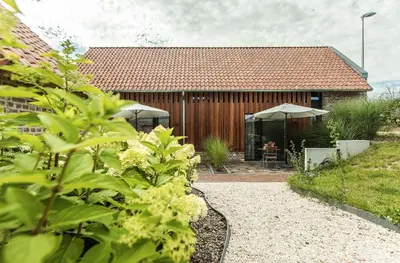 a house with a garden with a table and umbrella at Boerderaaj in Bilzen