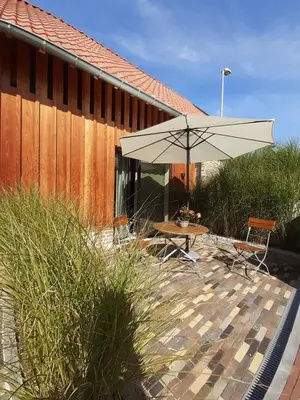 a patio with an umbrella and a table and chairs at Boerderaaj in Bilzen
