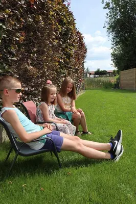 three young girls sitting in chairs in the grass at De Lokroep in Heers