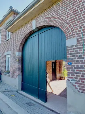 a blue garage door on the side of a brick building at Boerderaaj vakantiewoning in Bilzen