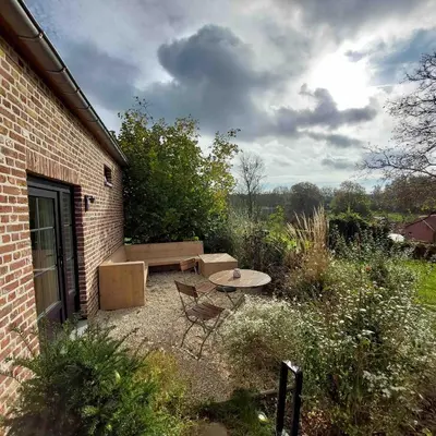 a patio with a table and a bench next to a brick building at Boerderaaj vakantiewoning in Bilzen
